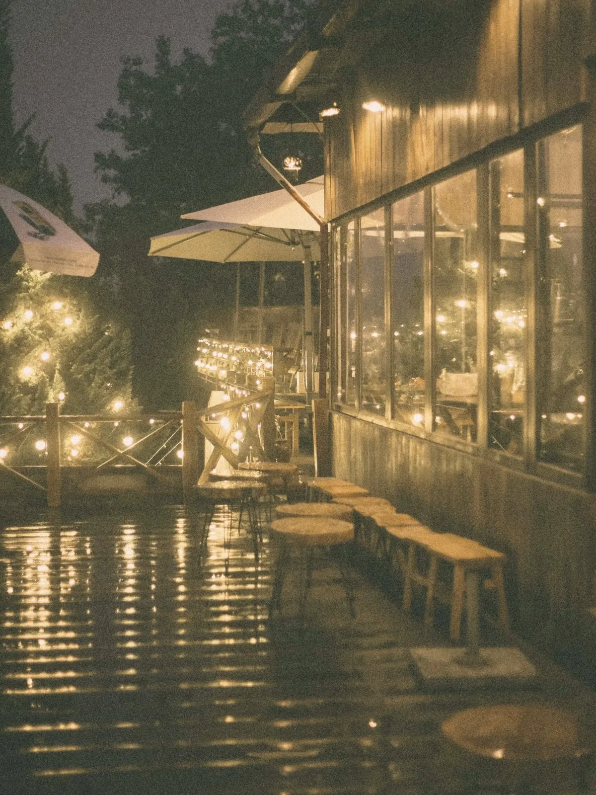 A café terrace lit with string lights on a rainy evening