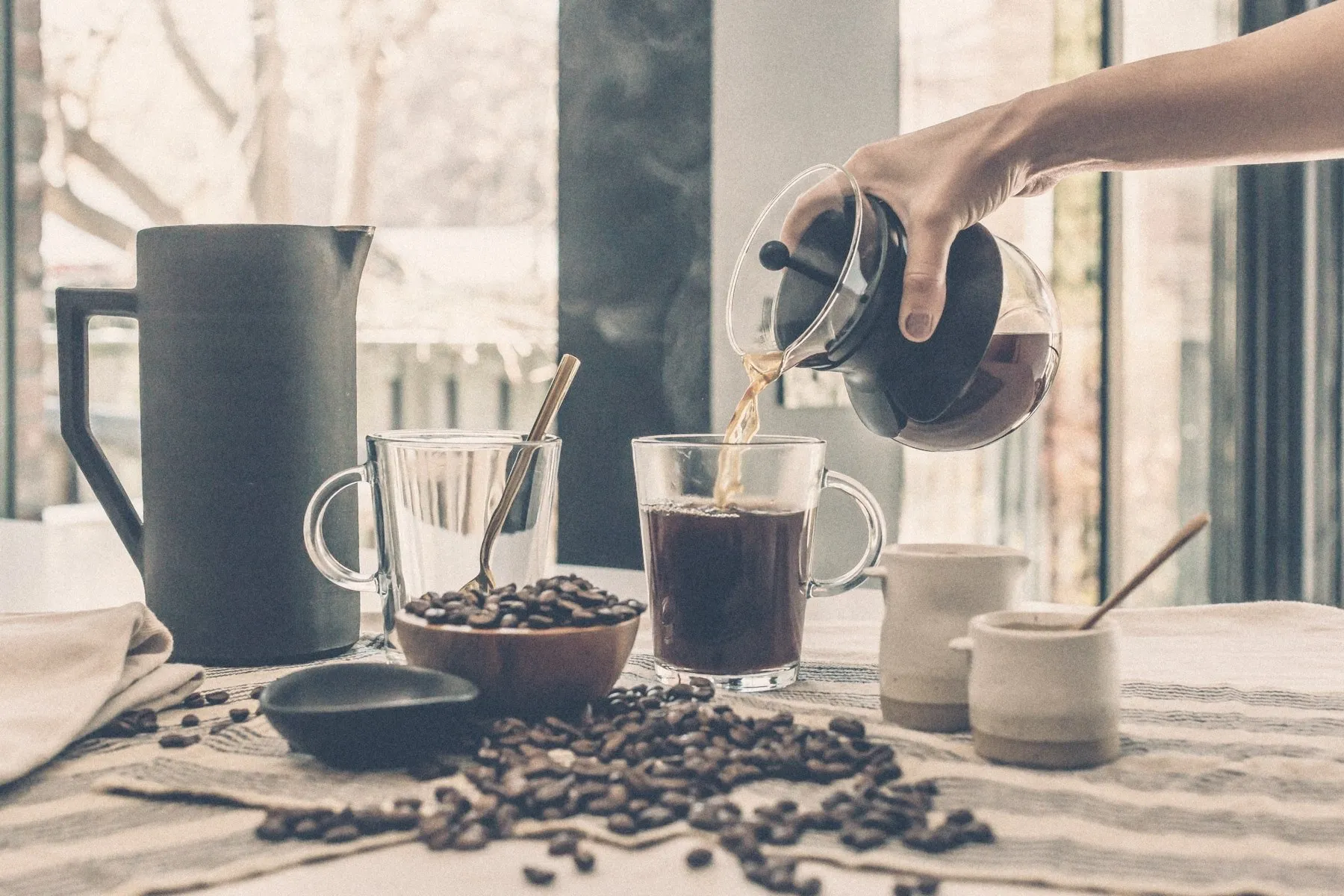 Coffee being poured on a table by a bright window
