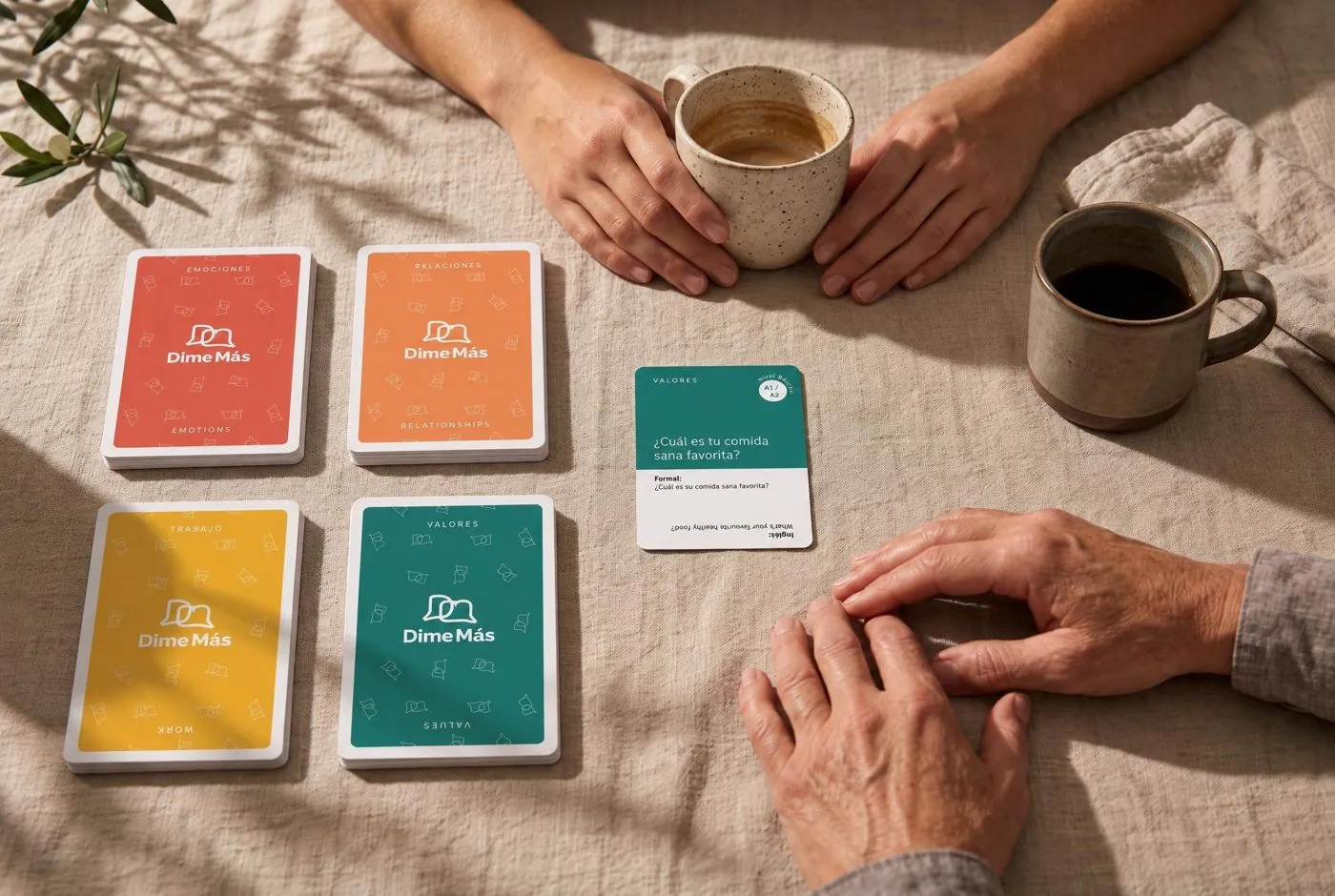 Two people at a table mid-game, Dime Más cards and coffee between them.
