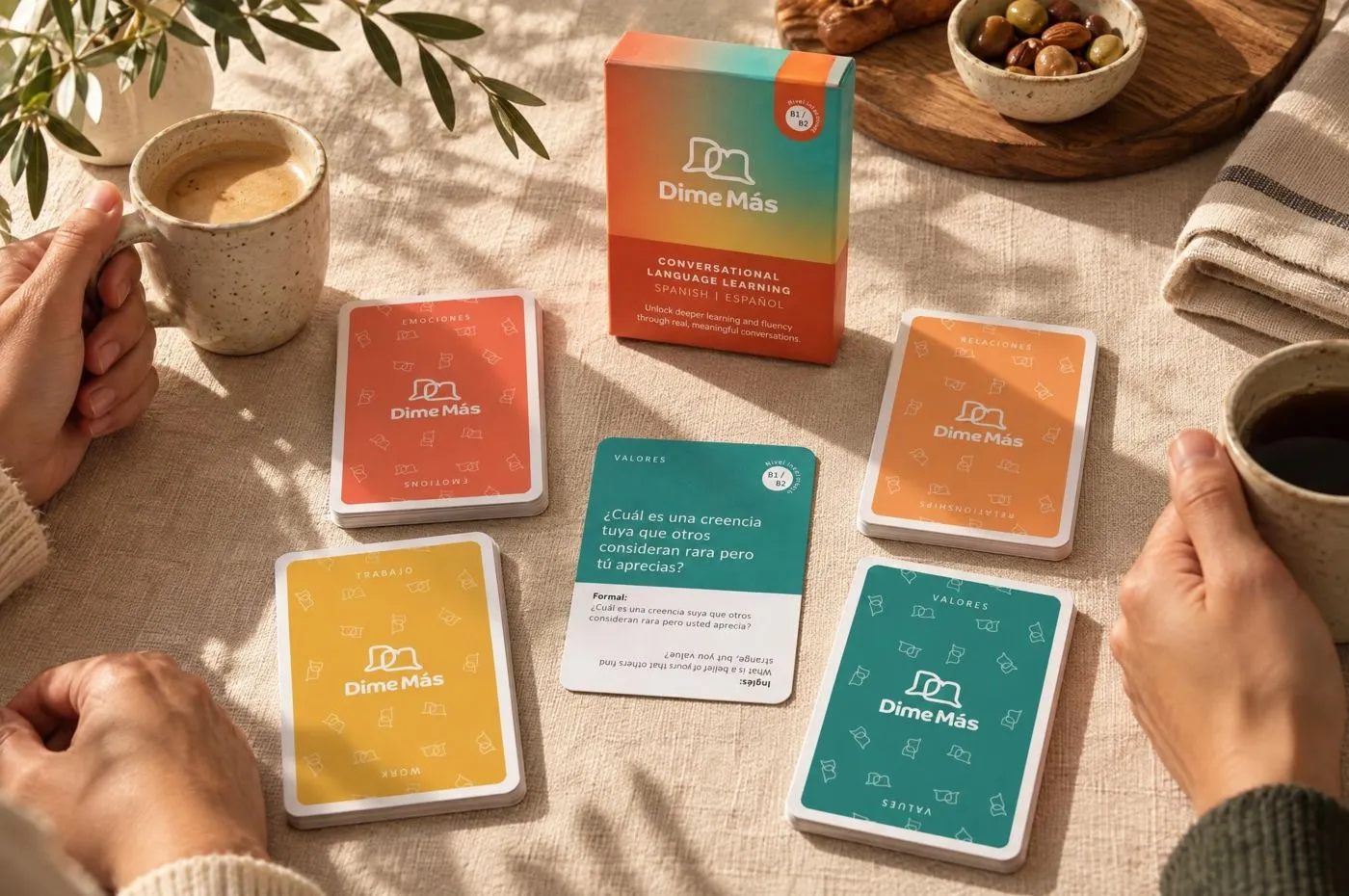 Dime Más cards in the middle of a game on a table, with coffee and hands