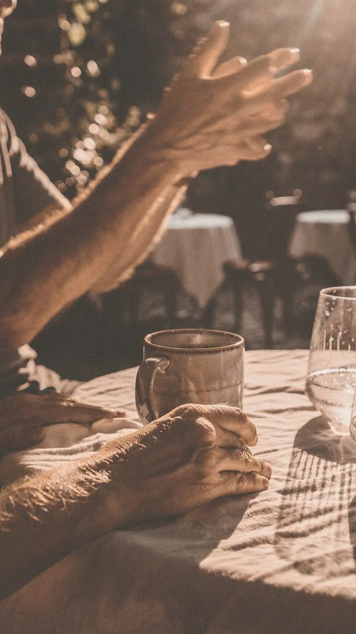 Two pairs of hands over coffee at a café table, mid-conversation.
