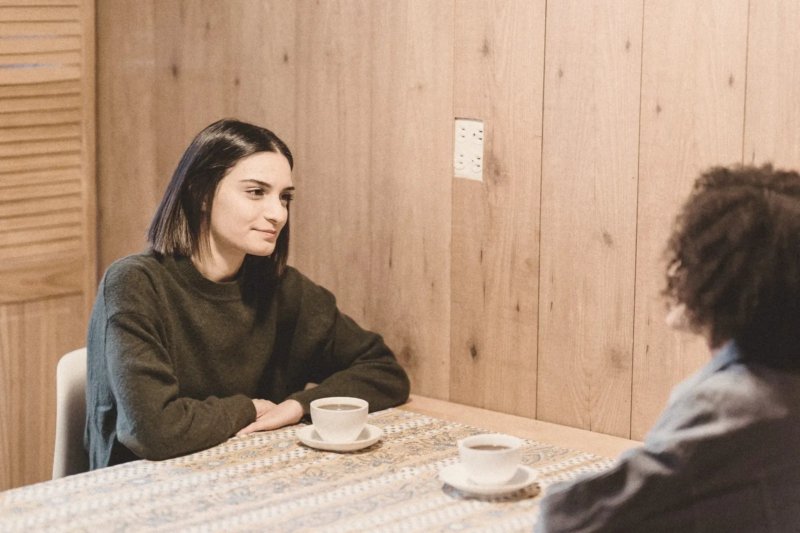 Two people talking across a table over coffee