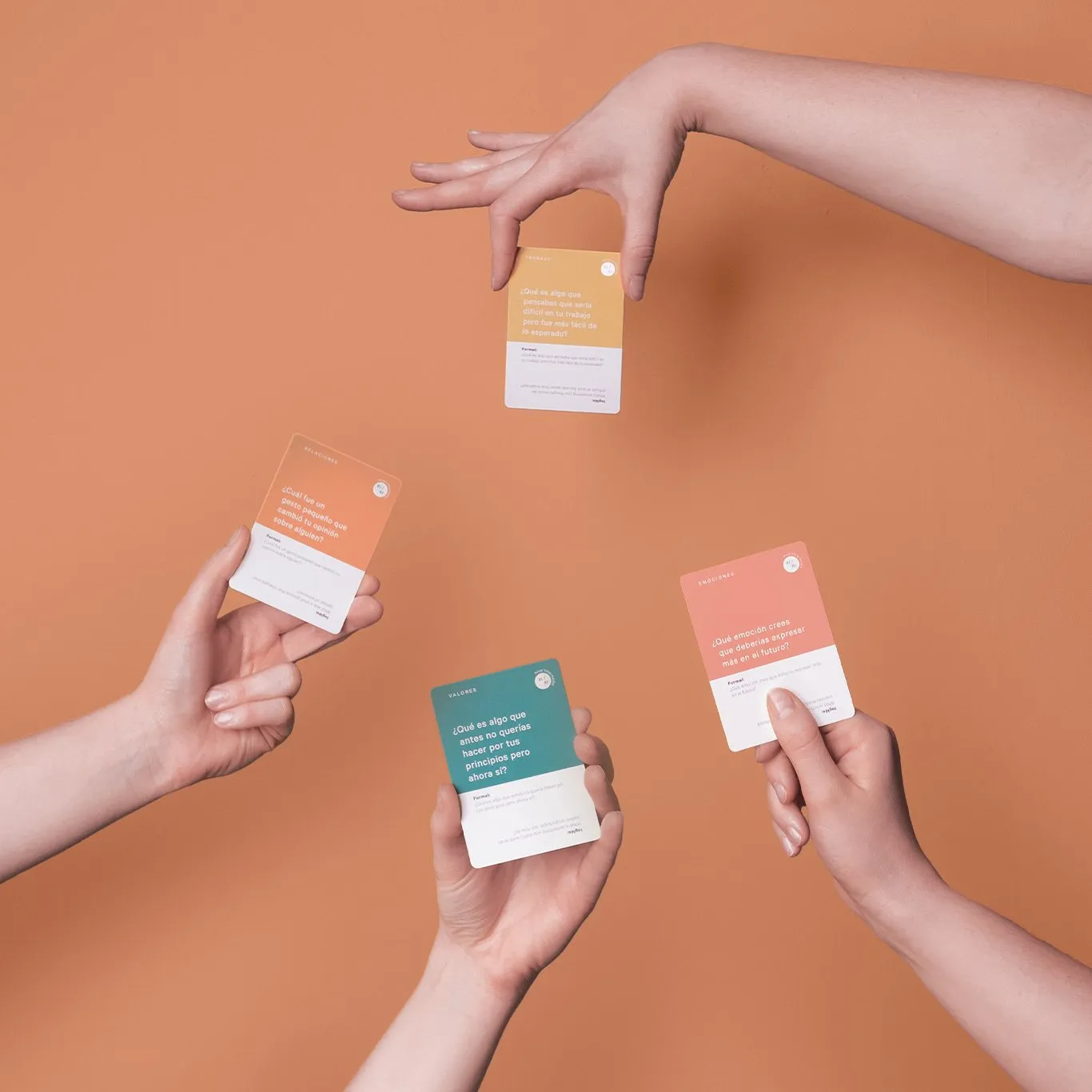 Hands holding Dime Más question cards against a warm peach background