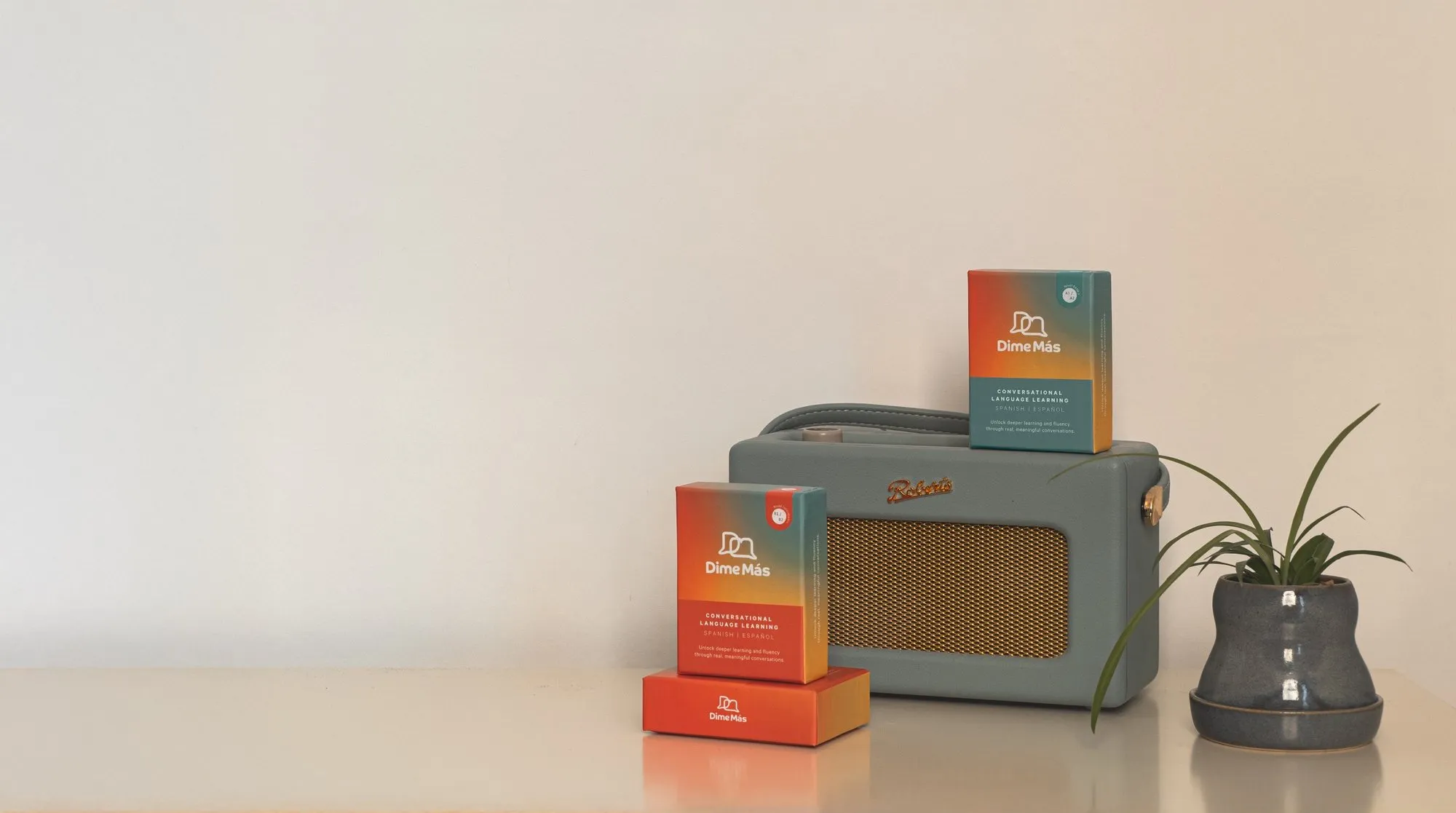 Dime Más card boxes on a shelf at home beside an old radio and a plant