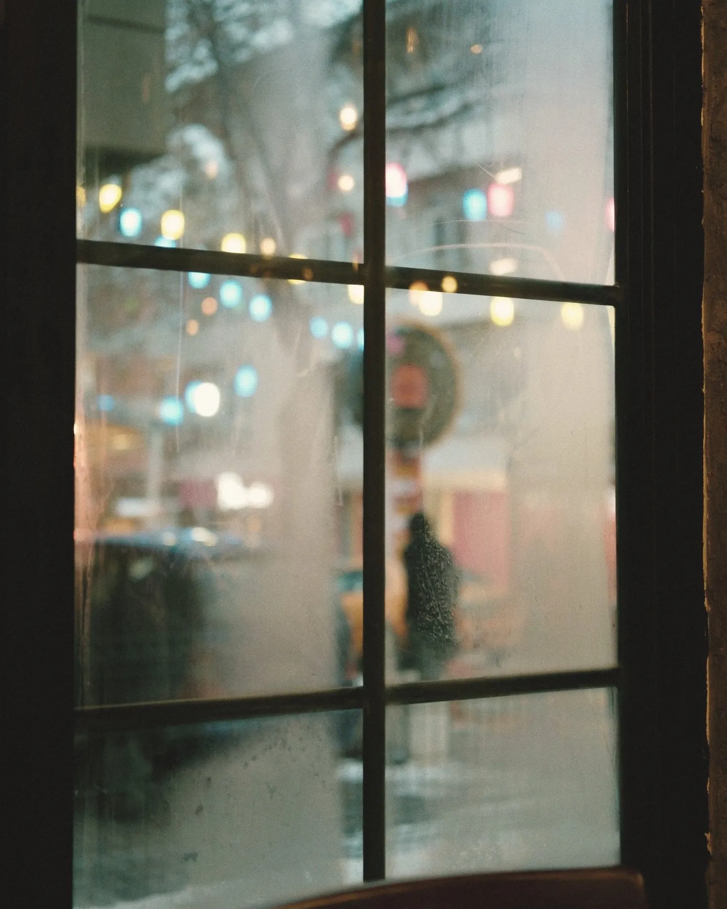 A steamed-up café window looking out onto a wet street